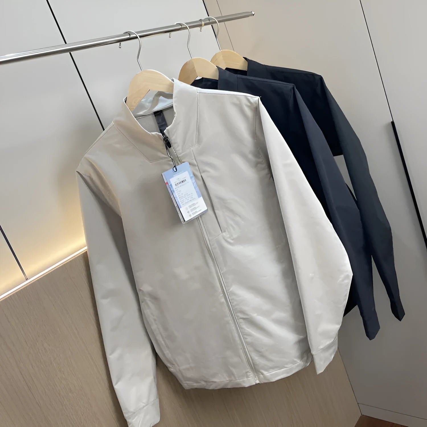 Men's beige stand collar casual sports jacket with long sleeves on a hanger.