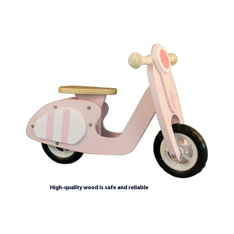 Pink wooden balance scooter for toddlers, 10 inches in size, on a flat surface.