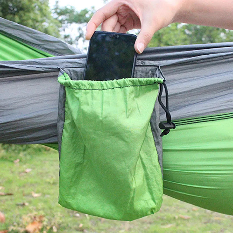 Blue parachute nylon outdoor hammock hung between two trees in a garden setting