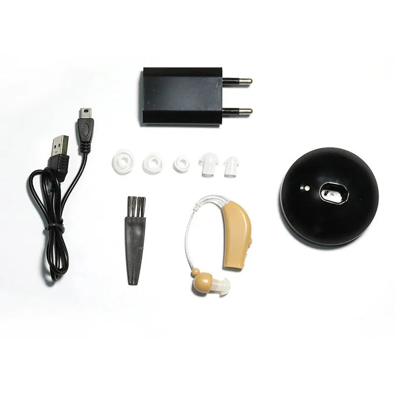 Black silicone rechargeable hearing aid amplifier with charging cable on a table.