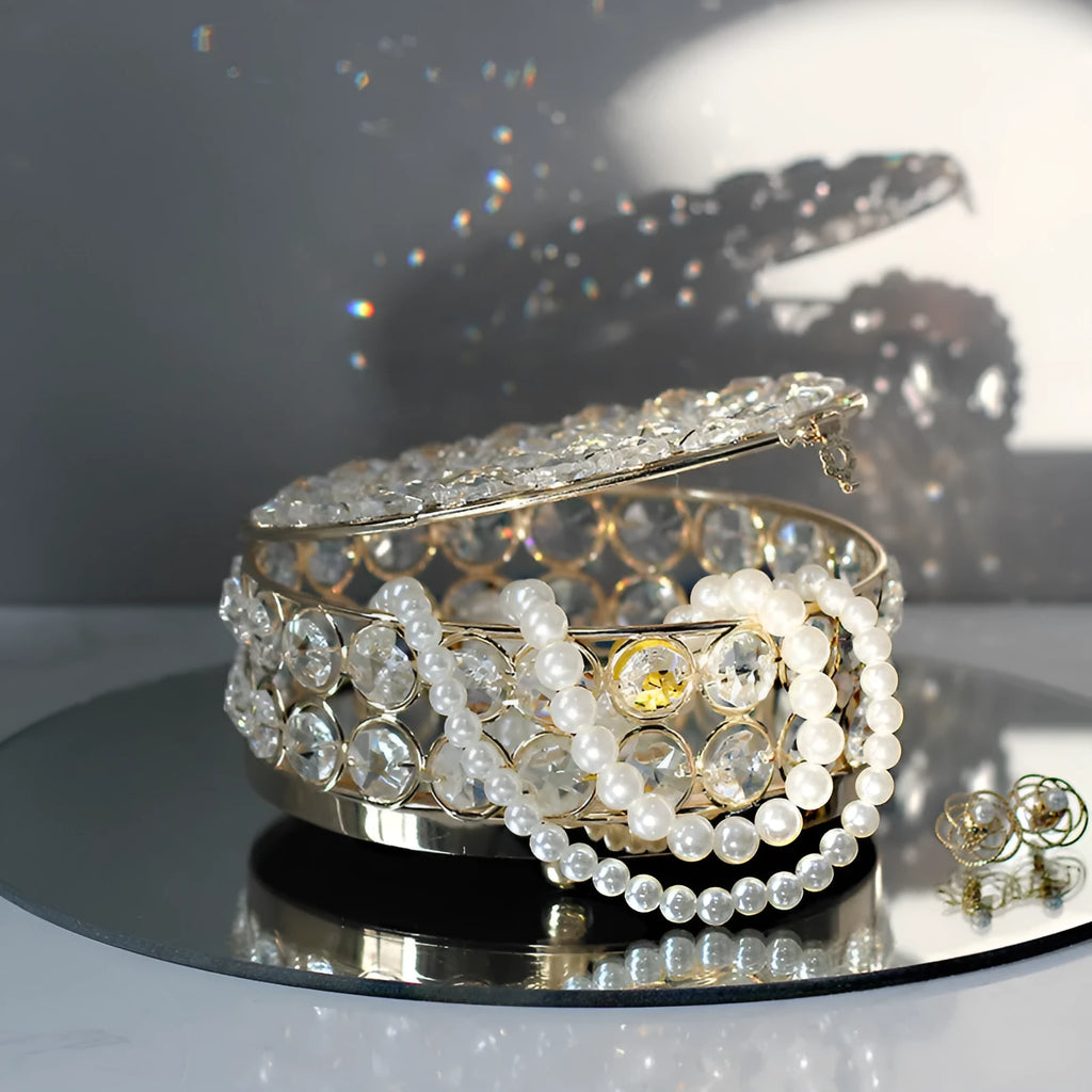 French gold iron jewelry storage box with a clear crystal glass lid on a wooden surface.