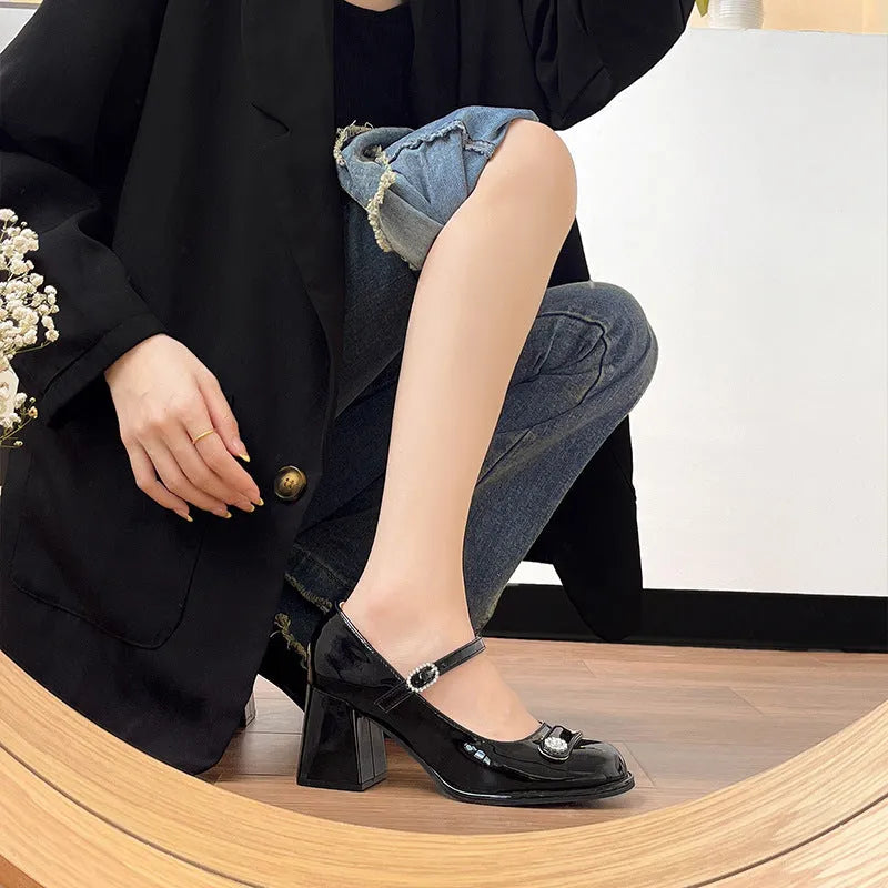 Women's black patent leather chunky heel sandals with round toe and buckle fastening.