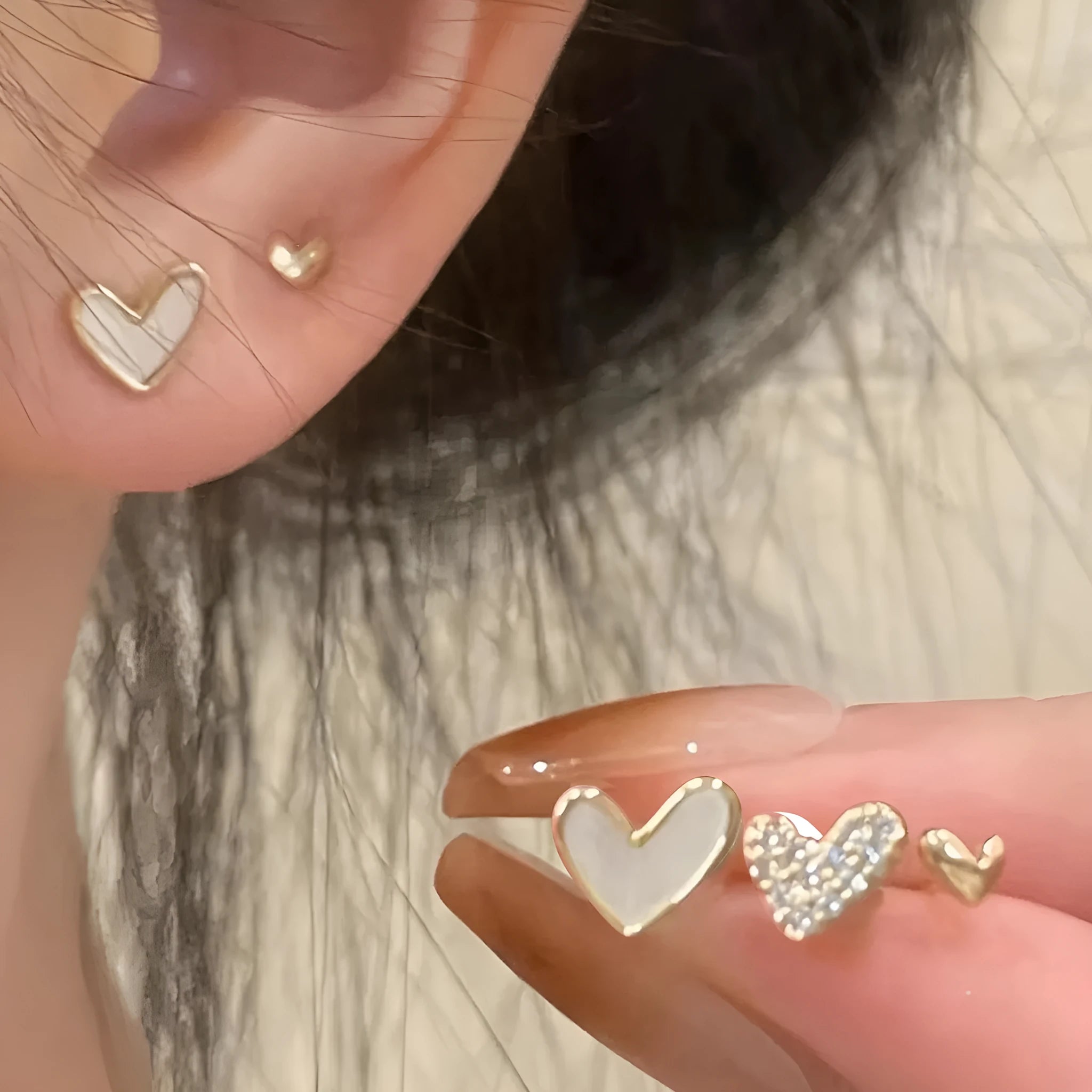 Three pairs of women's heart-shaped earrings in gold, black, black and white, and pink colours