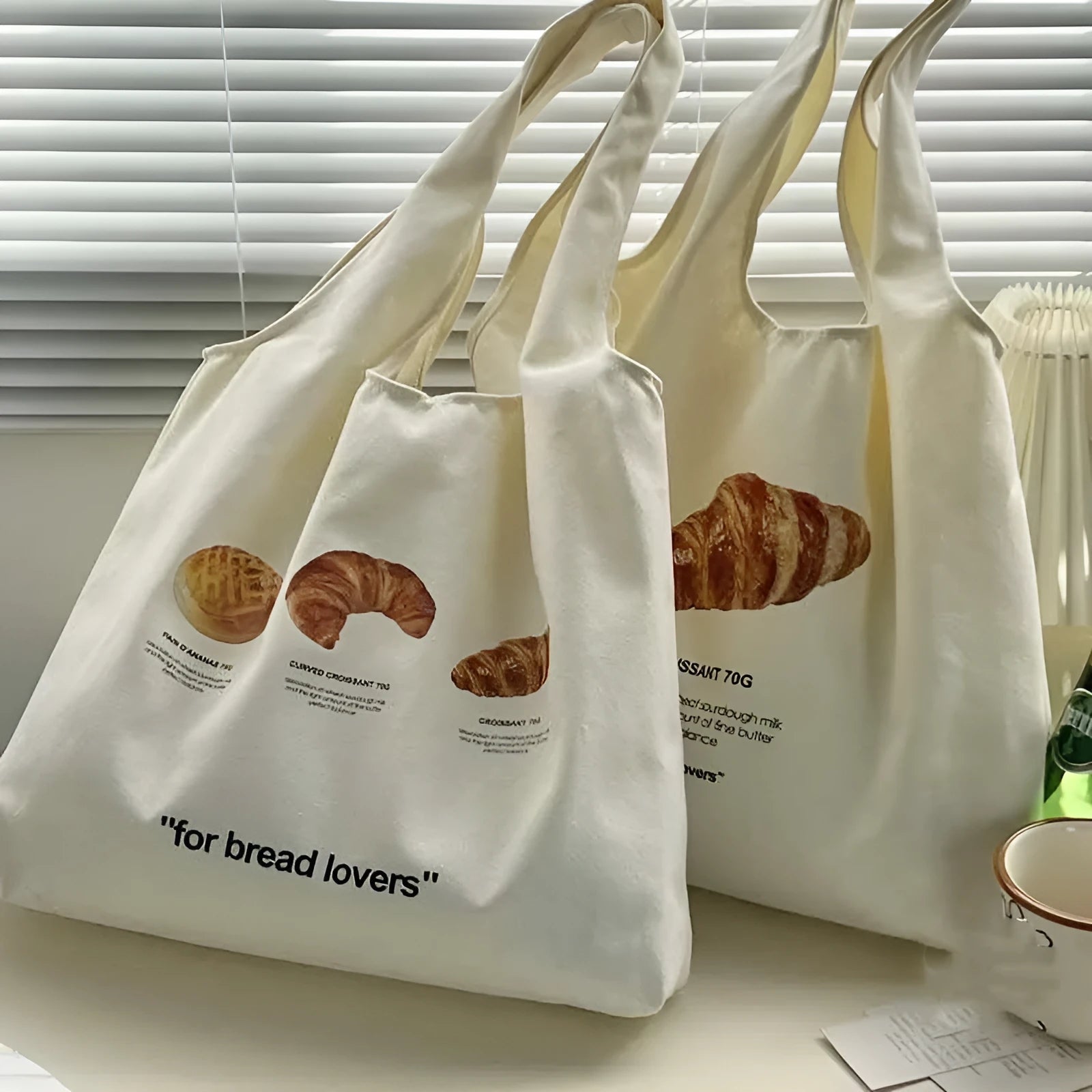 Beige canvas one-shoulder tote bag with printed bread and croissant designs
