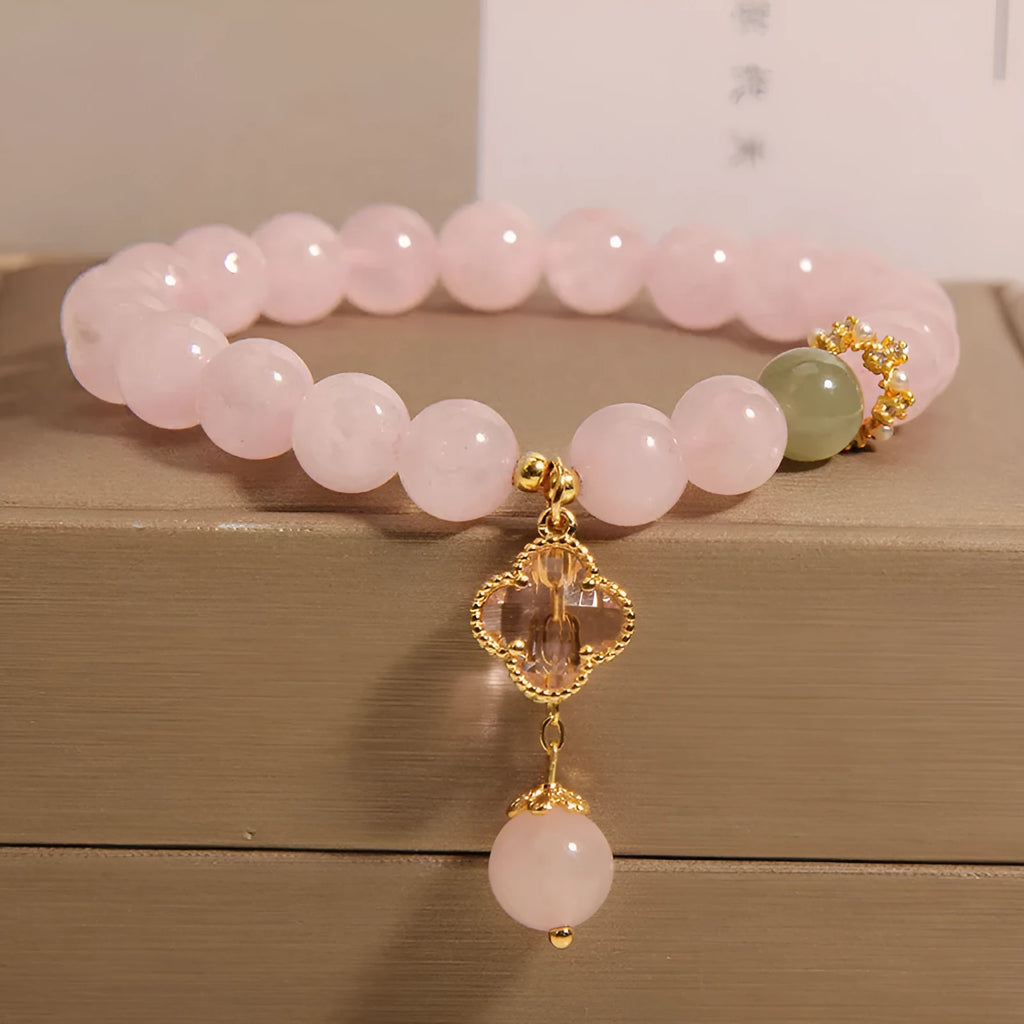 Pink women's bracelet with a crystal four-leaf clover pendant and rhinestone details on an adjustable chain.