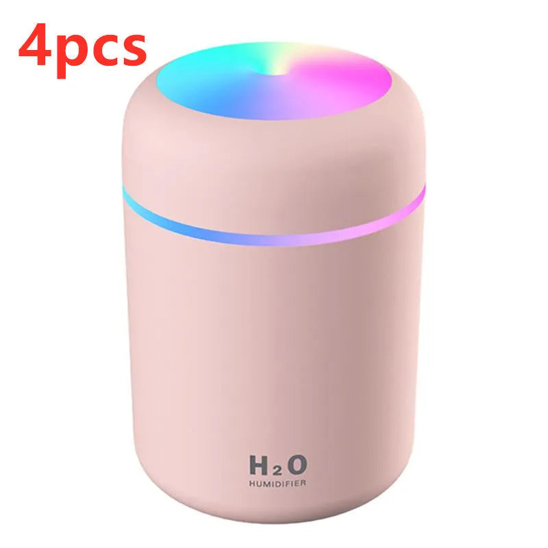 Pink, white, or navy blue USB mini desktop humidifier with atmosphere lights on a desk.
