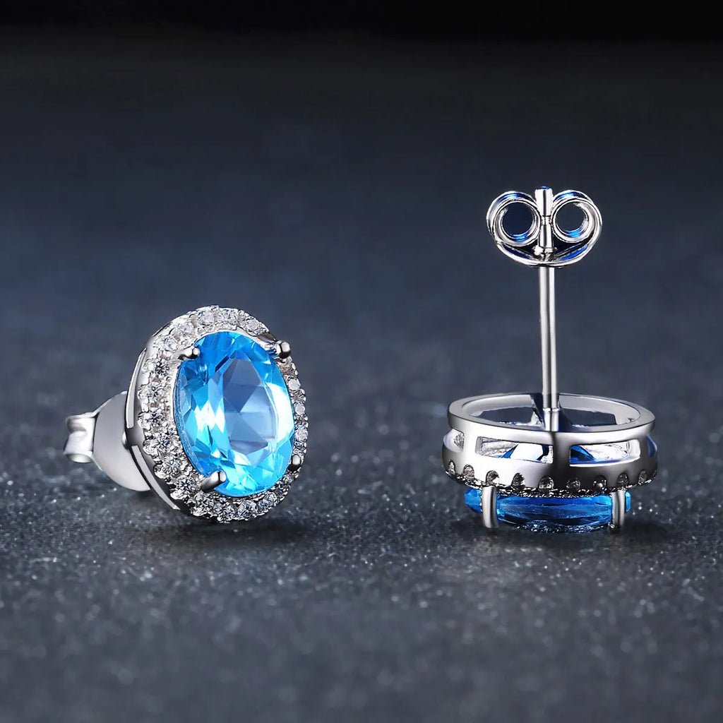 Four-piece sterling silver jewellery set with blue topaz gems showing geometric necklace, earrings, ring, and pendant