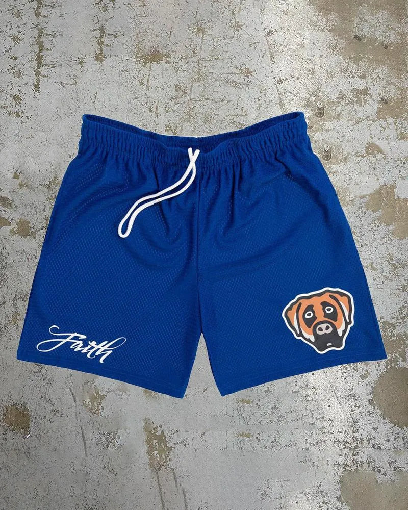 Man's loose blue digital print beach shorts with elastic waistband on a sandy background.
