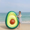 Large green inflatable avocado pool float on blue water, showing its 169cm length.