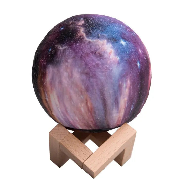3D-printed white lunar sphere night light with crater texture on a dark surface.