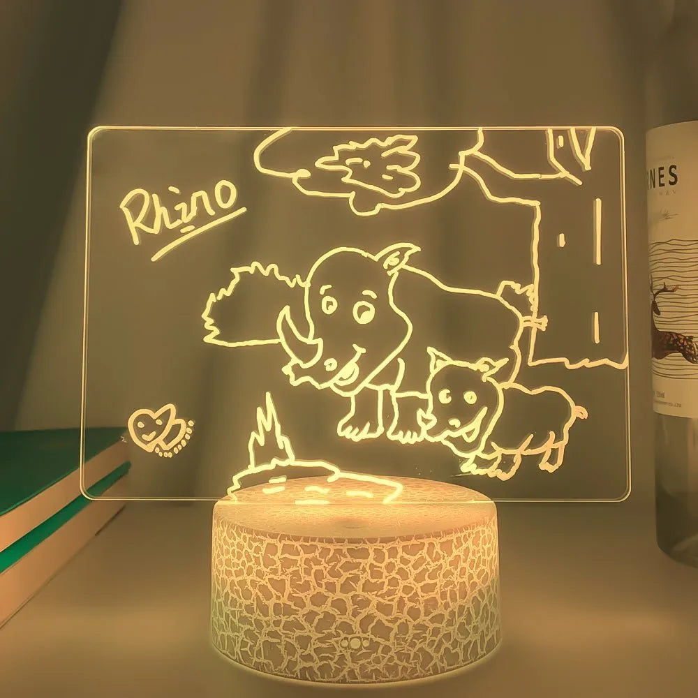 3D acrylic message board night light with remote control and stylus on a desk.