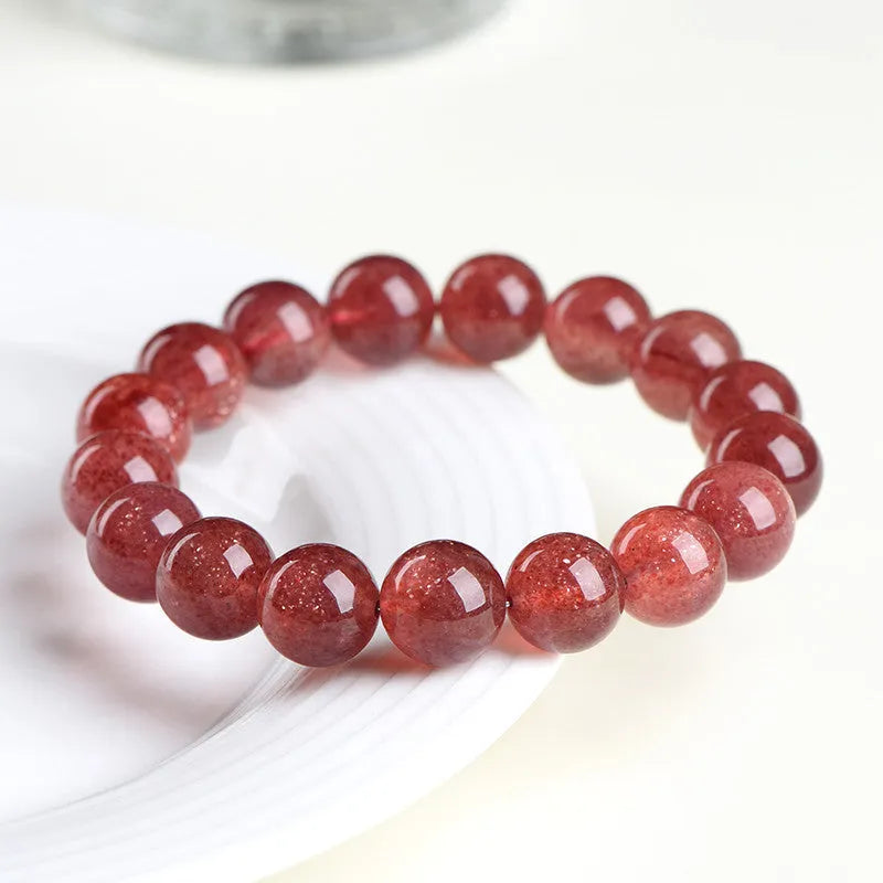 Natural cherry red strawberry quartz bracelet with geometric beads on a wrist.