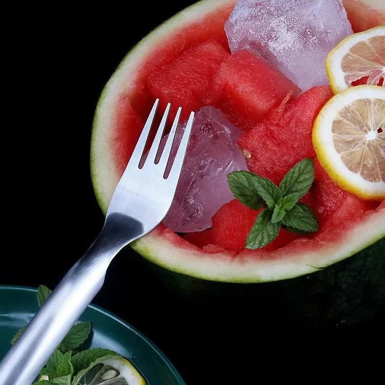 Silver stainless steel watermelon slicer and serving fork with a long handle on a kitchen surface