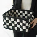 Black and white checkerboard patterned felt folding storage basket shown in its assembled box shape.