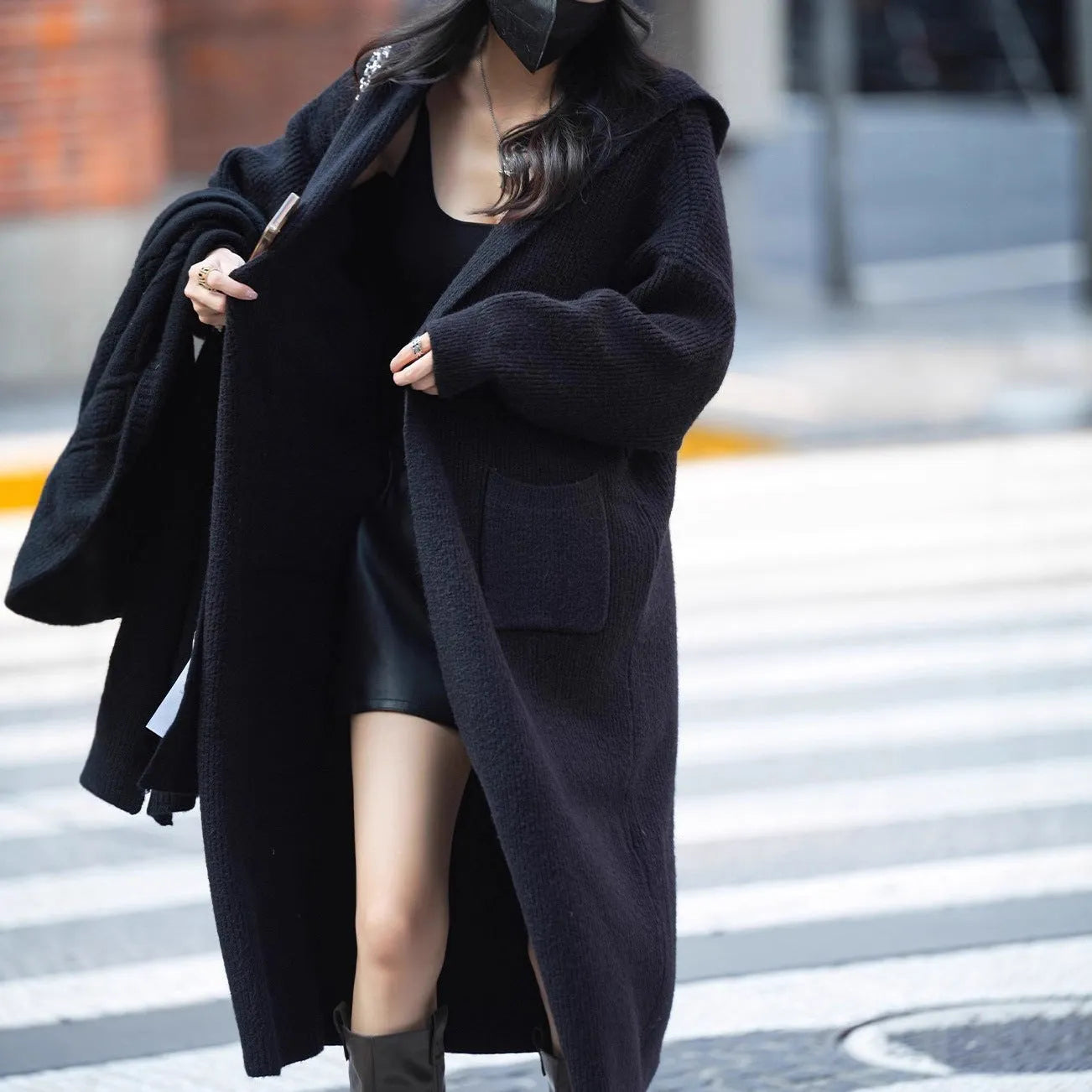 Long grey knitted cardigan with a hood, shown on a model, featuring a loose trench coat style.