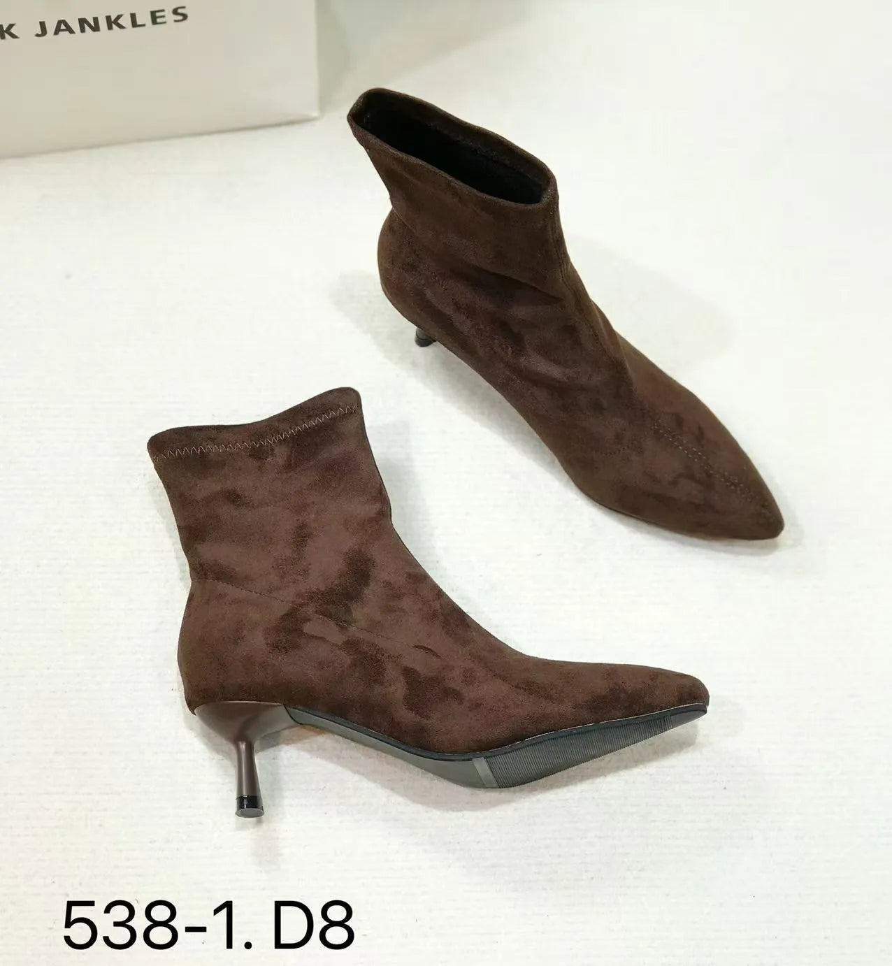 Black microfiber ankle boots with a stiletto heel and pointed toe on a mid-calf sock.