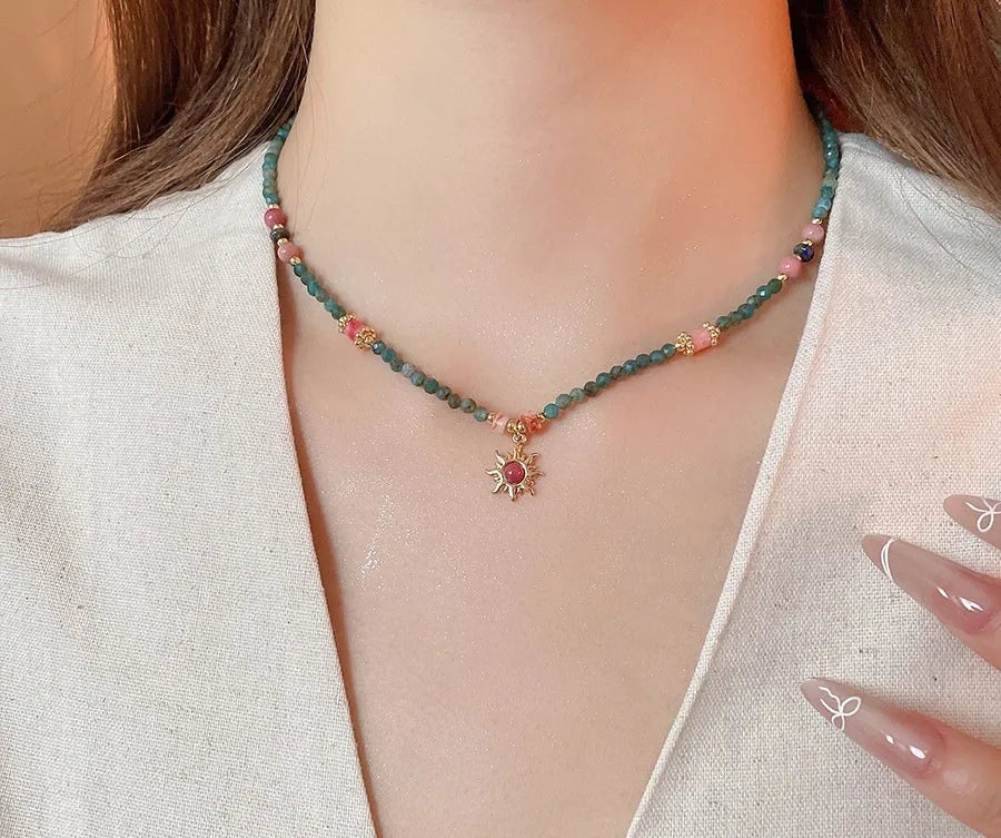 Freshwater pearl necklace with a blue stone sun pendant on an adjustable gold-toned chain.