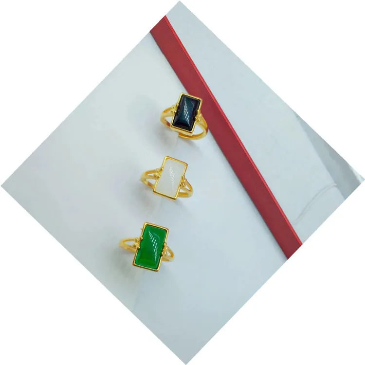 A gold-coloured adjustable ring with a large central green artificial gemstone, showing the national style design.