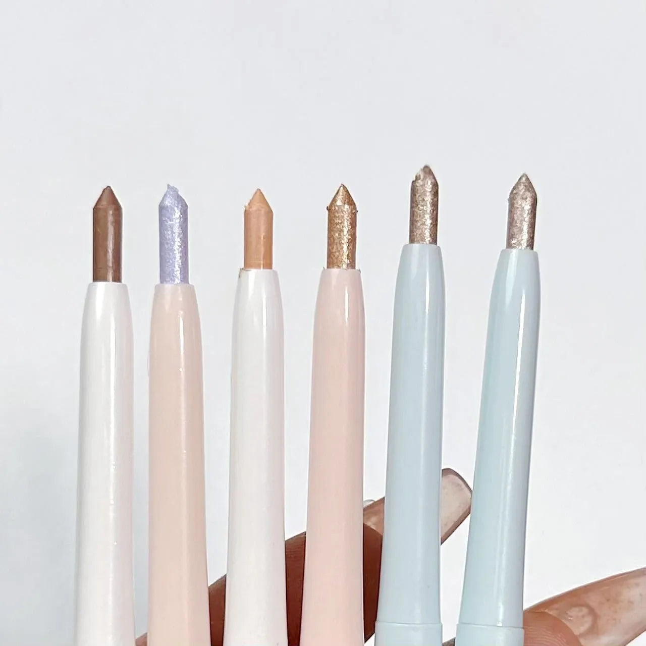 Waterproof 2-in-1 eye shadow pen showing various shades including gold, purple, and brown.