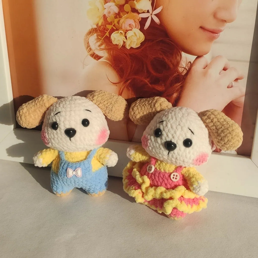 A pair of wool zodiac dog pendant charms on keychains, one wearing a strap skirt and the other strap pants.
