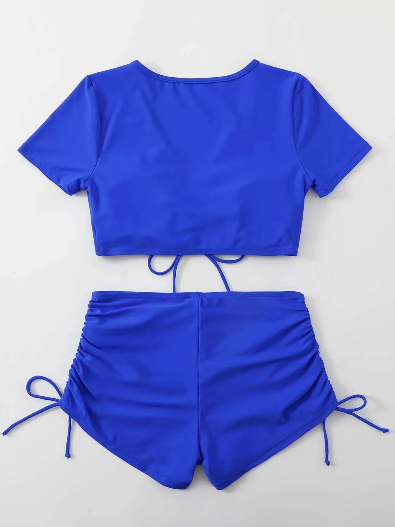 Women's dark green lace-up bow swimsuit top with matching shorts laid flat