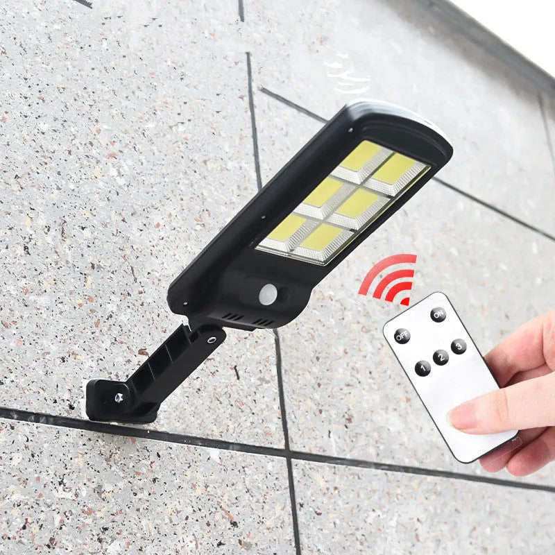 Black solar-powered outdoor security light with motion sensor on a wall