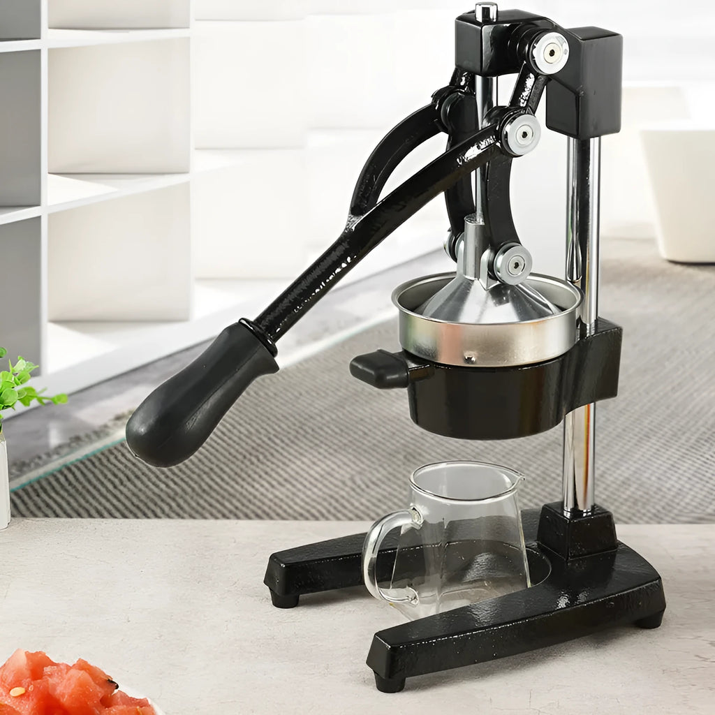 Black cast iron manual citrus juicer with stainless steel strainer on a kitchen counter.