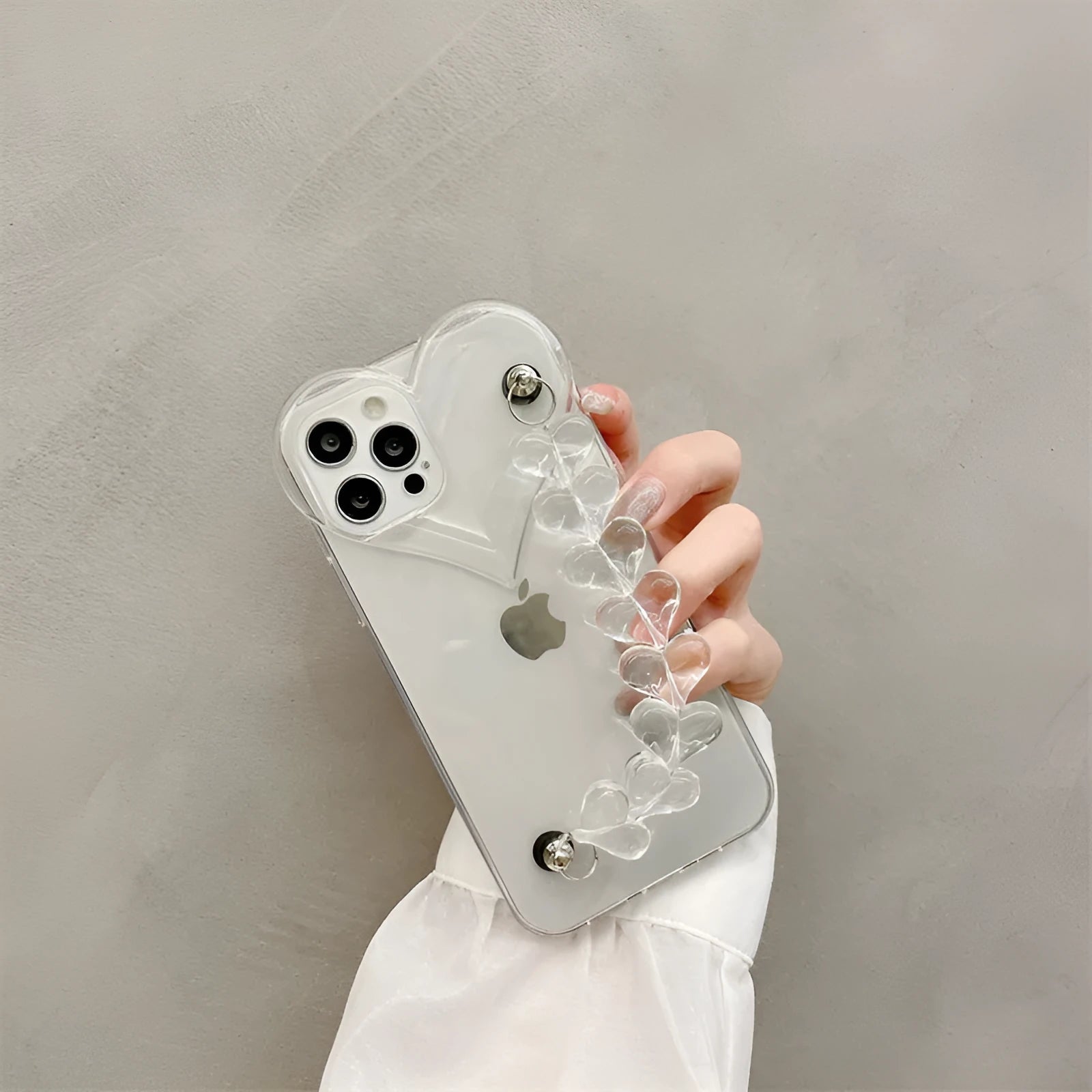 Transparent soft TPU iPhone case with a built-in clear love heart charm and chain.