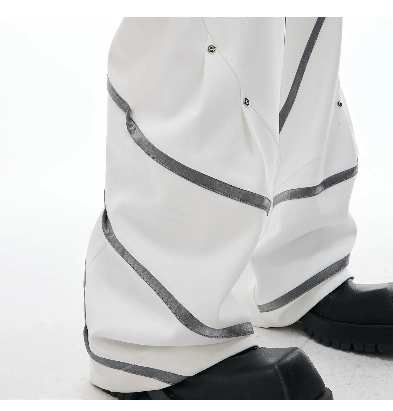 Men's black polyester trousers with metal striped rivet details and pleated front.