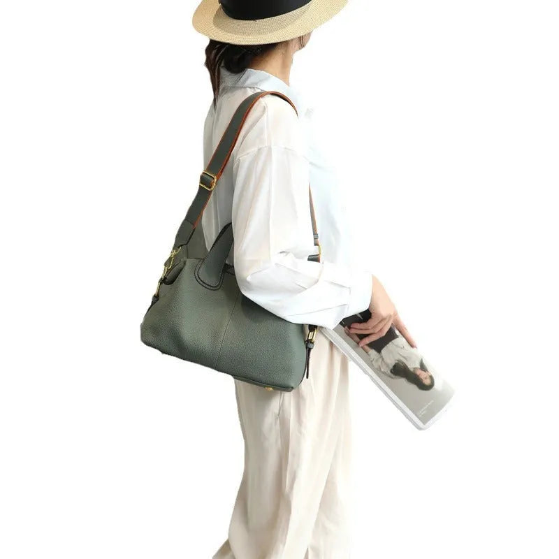 Women's leather cross-body bag in horizontal square shape with visible sewing thread detailing and interior compartments