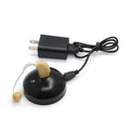 Black silicone rechargeable hearing aid amplifier with charging cable on a table.