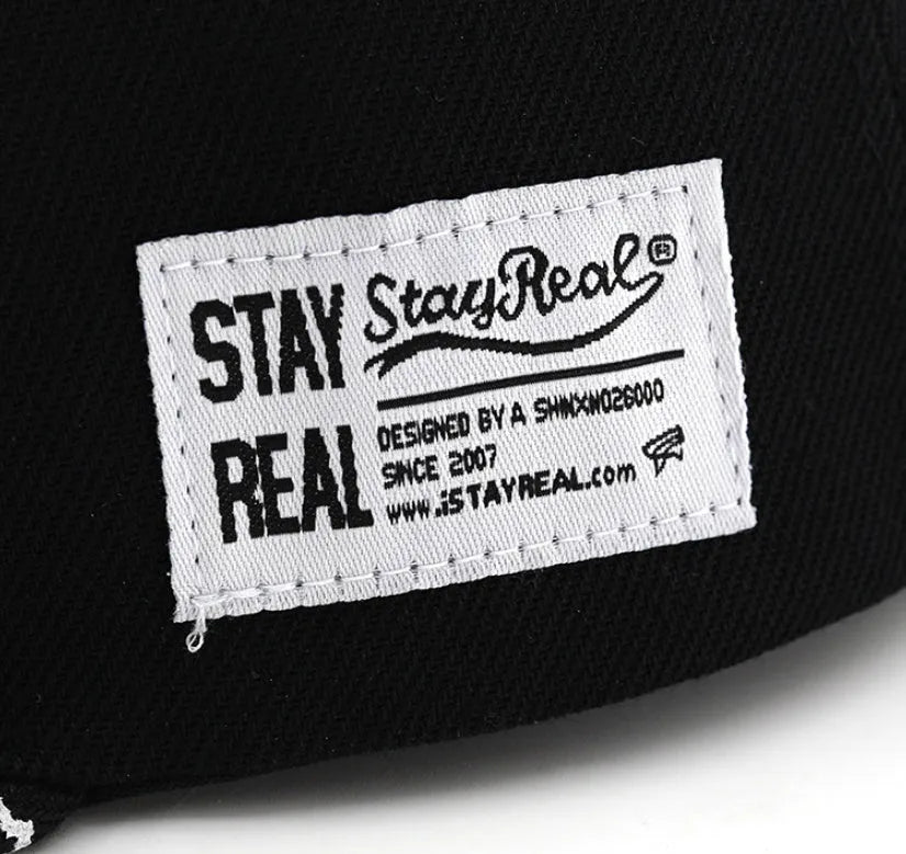 A black cotton baseball cap with embroidered lettering on the front, showing the adjustable strap at the back.