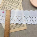 Cotton embroidered lace trim on roll showing cutout pattern, with width measurement examples
