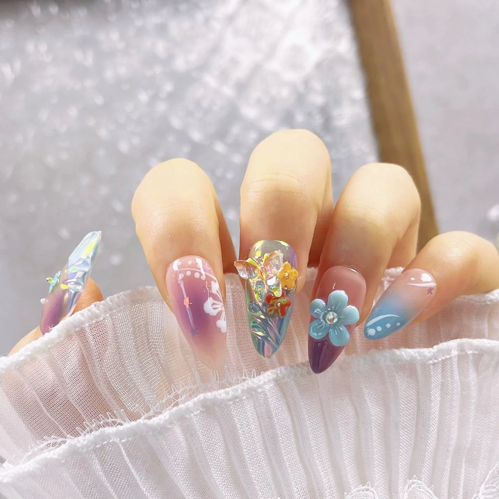 Handmade colourful flower and butterfly sculpture nail art stickers on almond-shaped false nails.