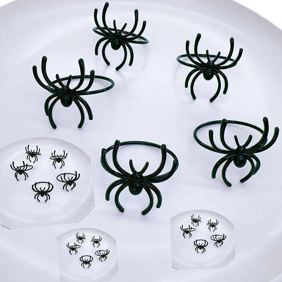 Six black metal spider-shaped napkin rings for Halloween table decoration.