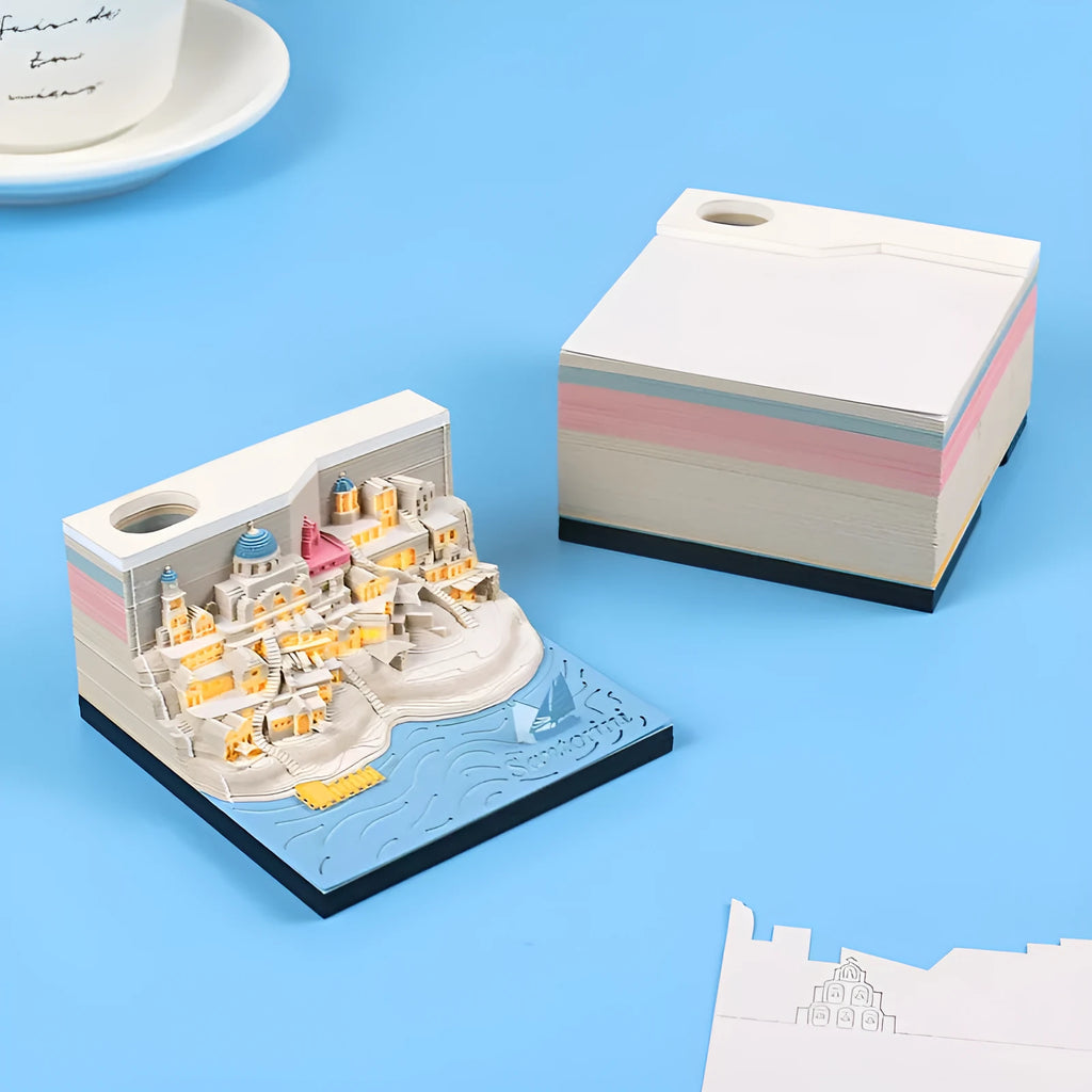 Assembled Santorini beach 3D paper model notepad with decorative lighting on a desk.