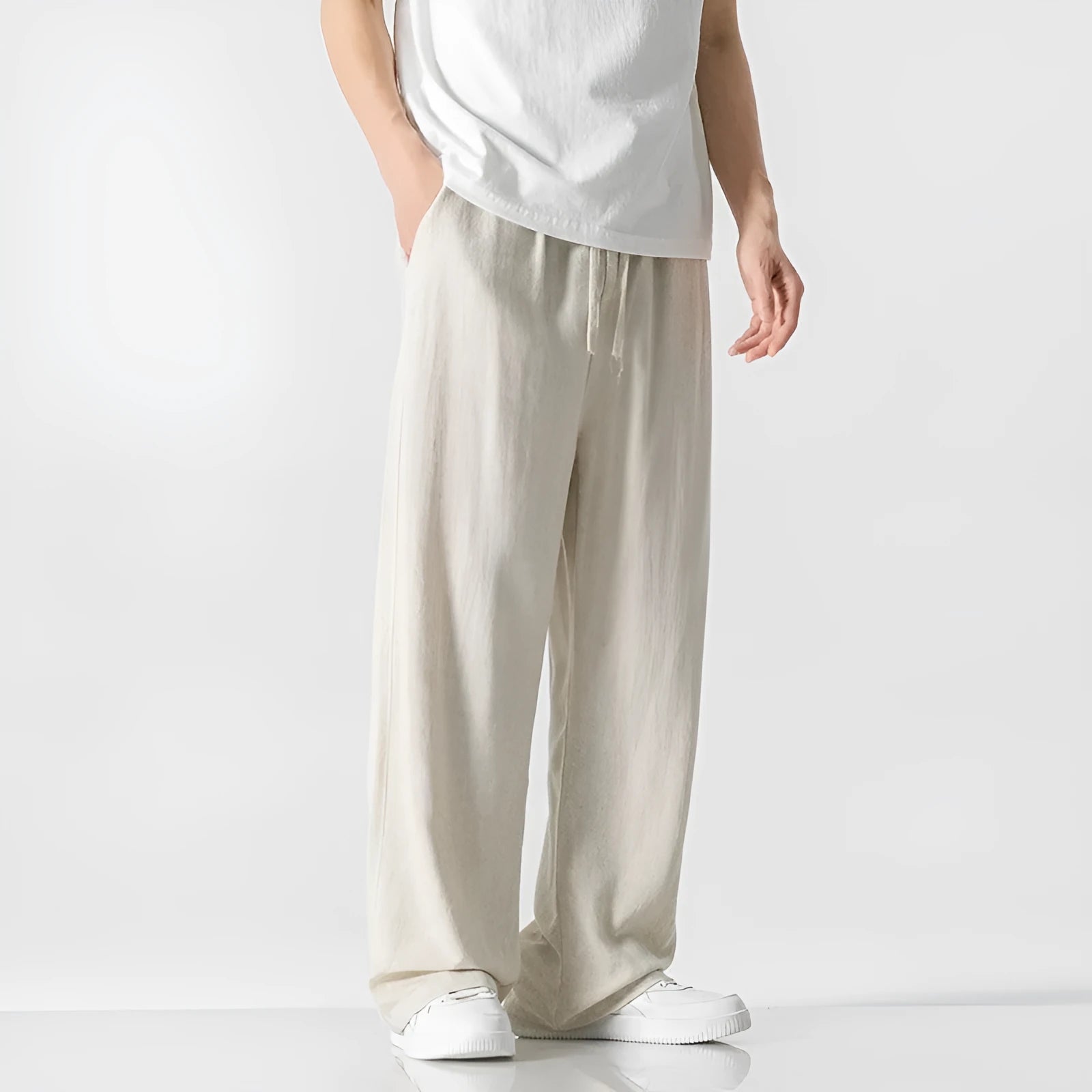 Man wearing beige loose-fit straight-leg cropped trousers with a drawstring waist.
