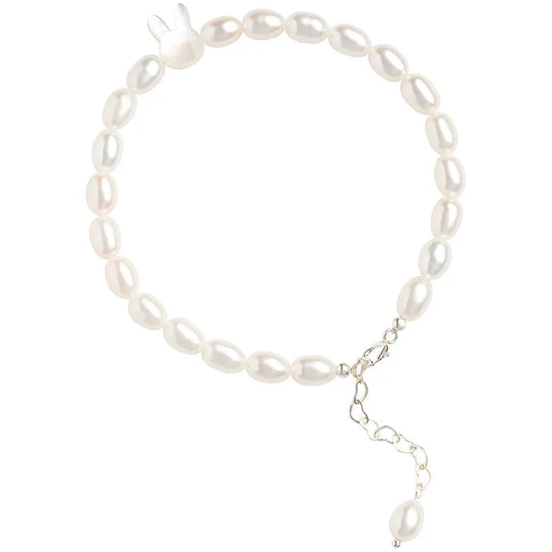 White shell pearl elastic bracelet with 925 silver rabbit charm on wrist showing rice-shaped beads and adjustable closure