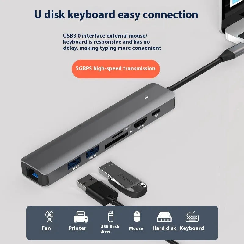 Silver aluminium 7-in-1 USB hub with SD card slot, microSD slot, USB-C PD port, and multiple USB-A ports.