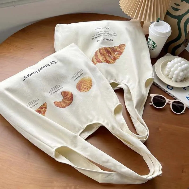 Beige canvas one-shoulder tote bag with printed bread and croissant designs