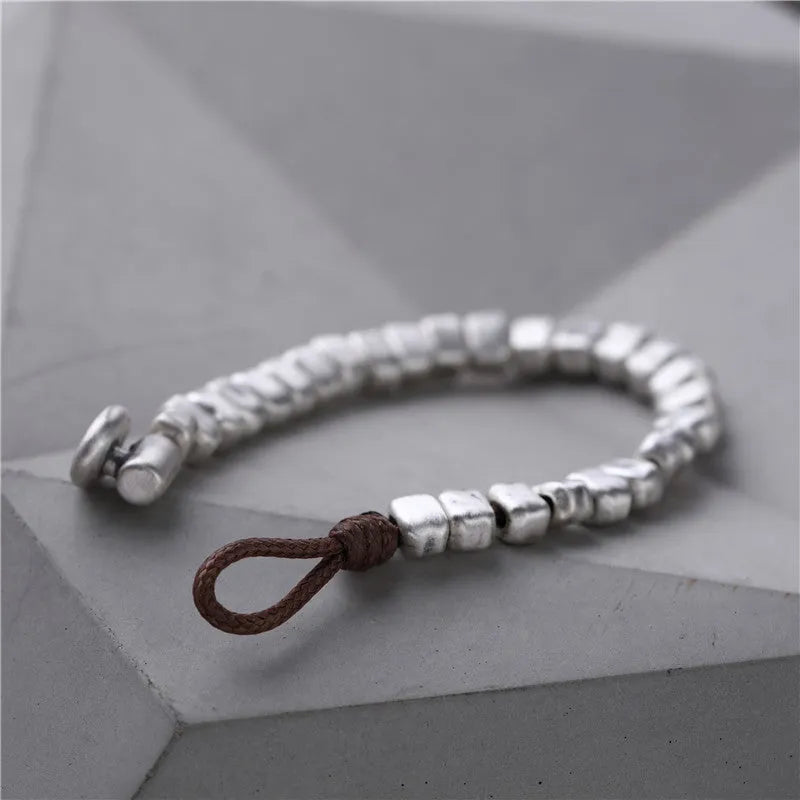 Handmade silver bracelet with an irregular square design and wooden details on an elasticated band.