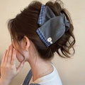Handmade triangle-shaped hair clip for women in fabric and acrylic, showing plastic grip.
