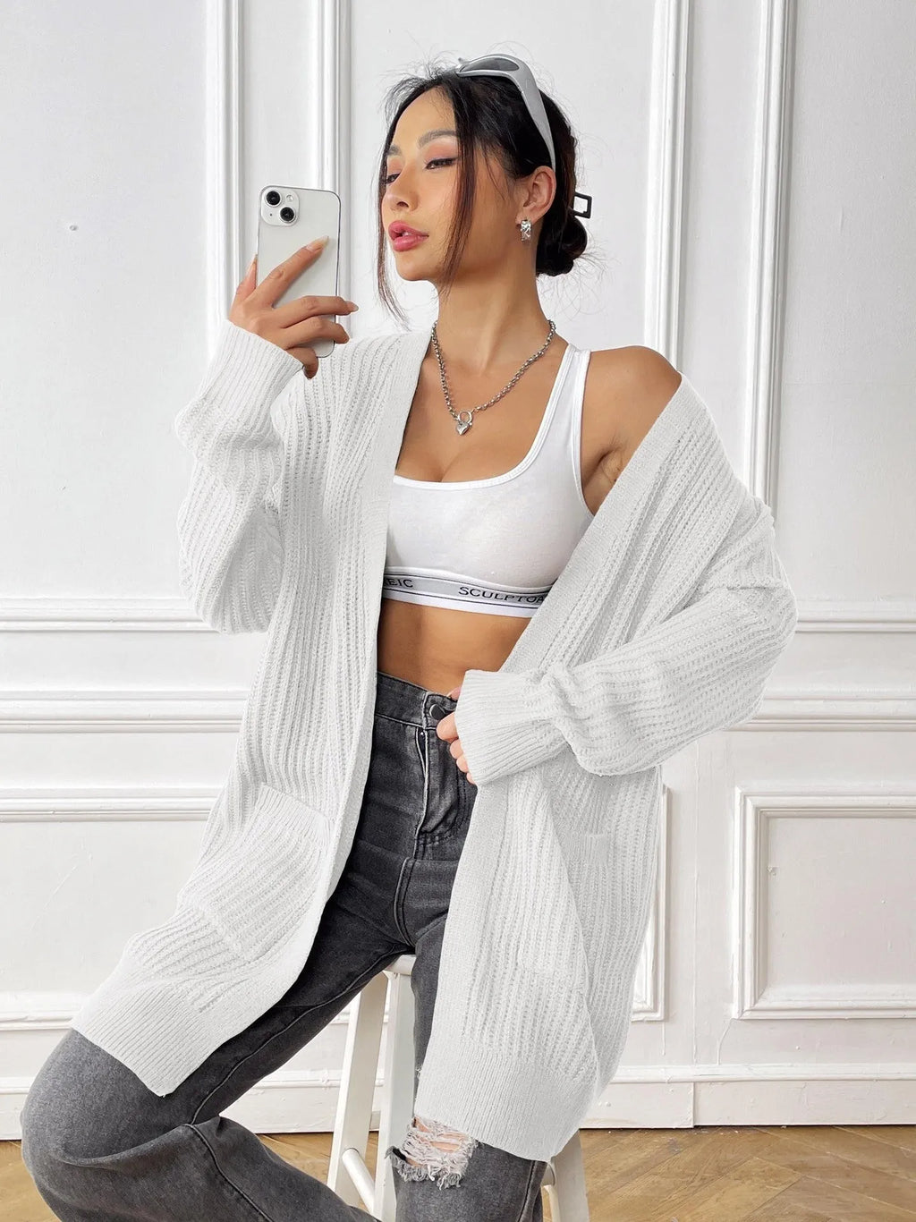 A woman's loose-fit mid-length cardigan in a solid colour, shown on a hanger.