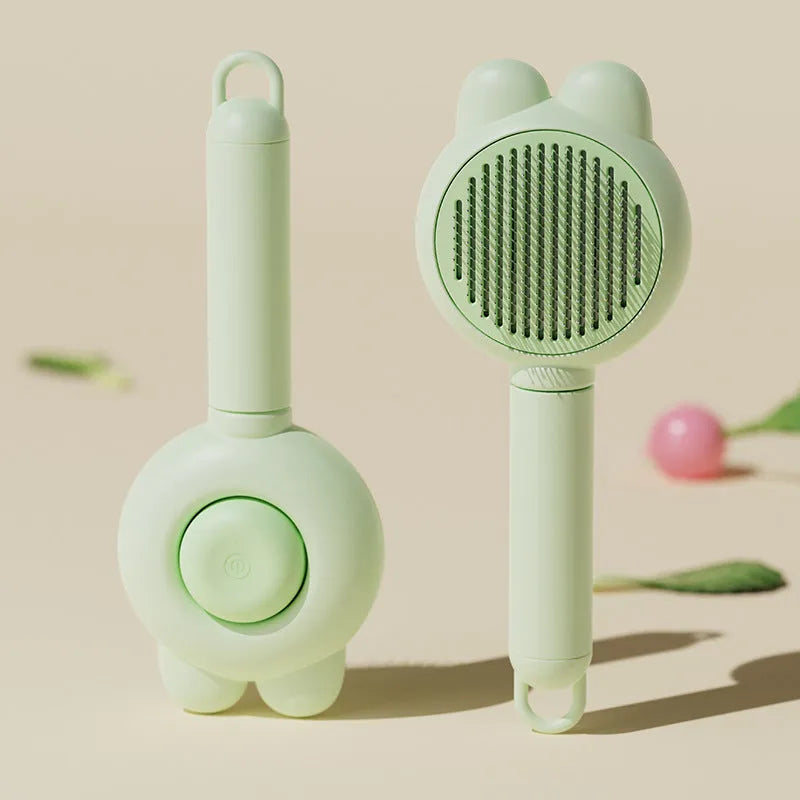 Self-cleaning pet brush with green handle and stainless steel teeth, showing release button mechanism