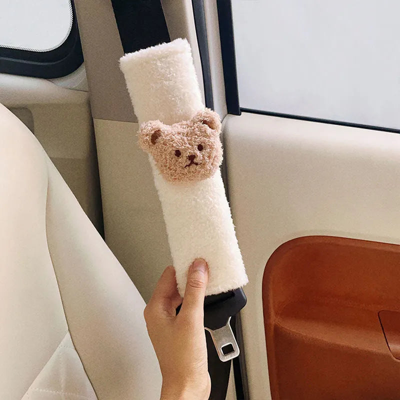 Close-up of a khaki-coloured plush bear seat belt cover on a car seat strap.