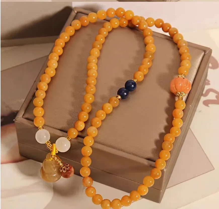Women's multi-circle bracelet with three strands of natural Jinsi Jade beads and a resin flower calabash pendant on a white background