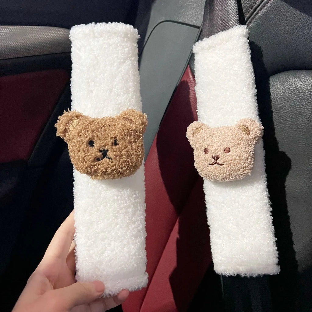Close-up of a khaki-coloured plush bear seat belt cover on a car seat strap.