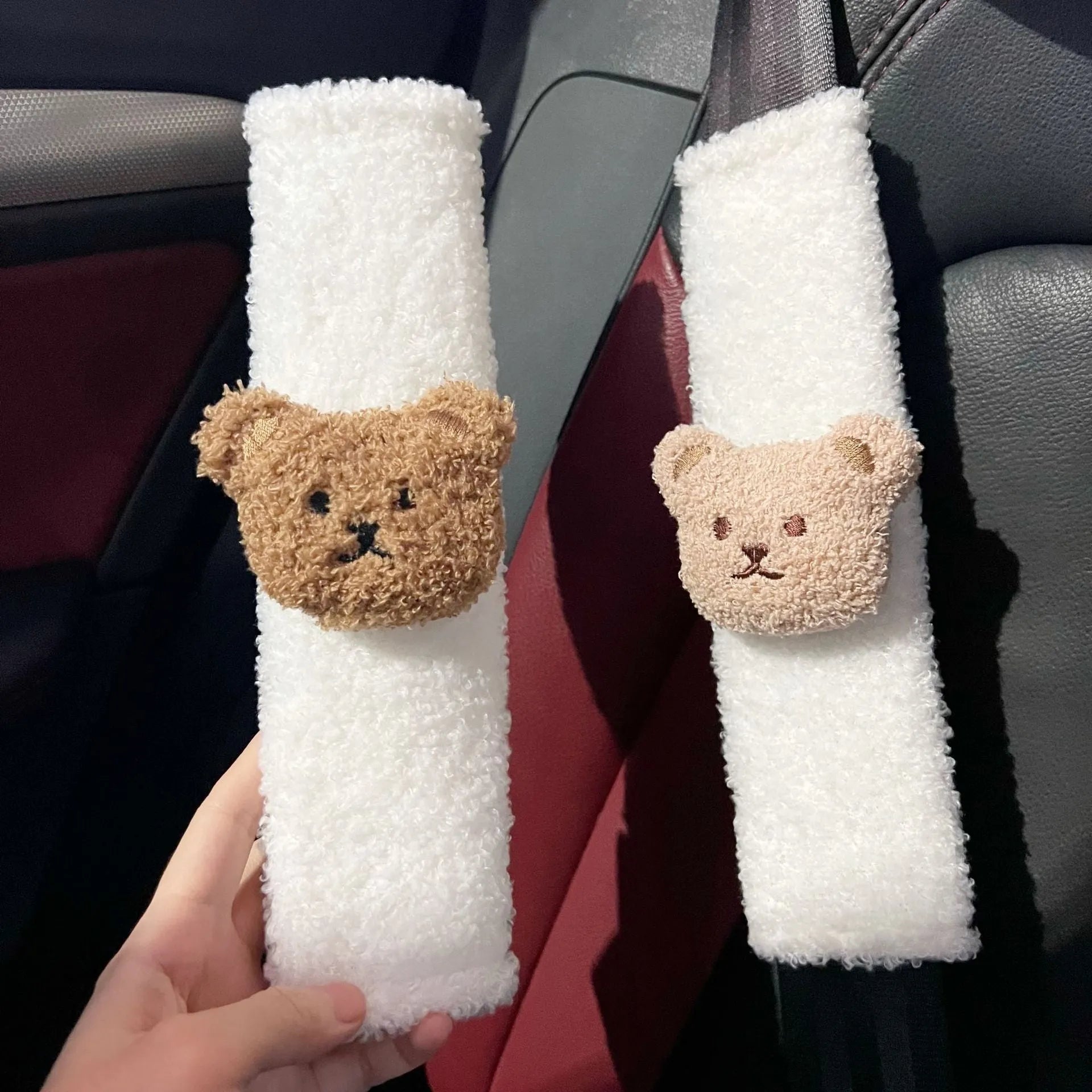 Close-up of a khaki-coloured plush bear seat belt cover on a car seat strap.