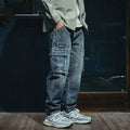 A pair of men's loose straight leg blue jeans on a plain background, showing the zip fly and classic denim style.