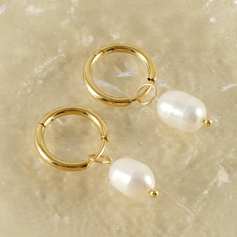 Geometric gold-coloured stainless steel earrings with a white pearl detail on a white background.